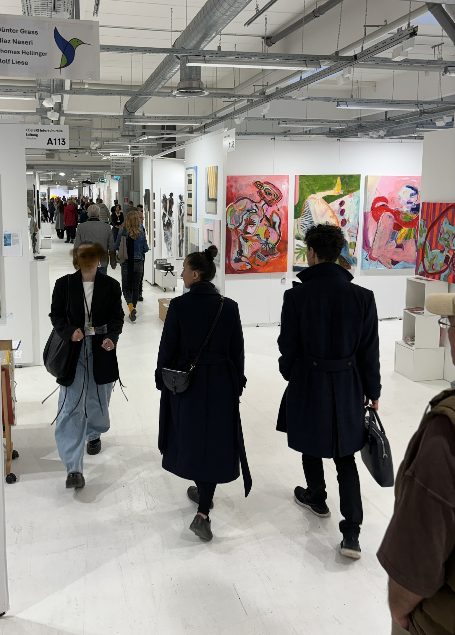 Kunstmesse mit Besuchern vor Acrylbildern, worüber in Künstlerkreisen niemand spricht.